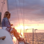 Couple of cheerful girls are enjoying their trip on yacht